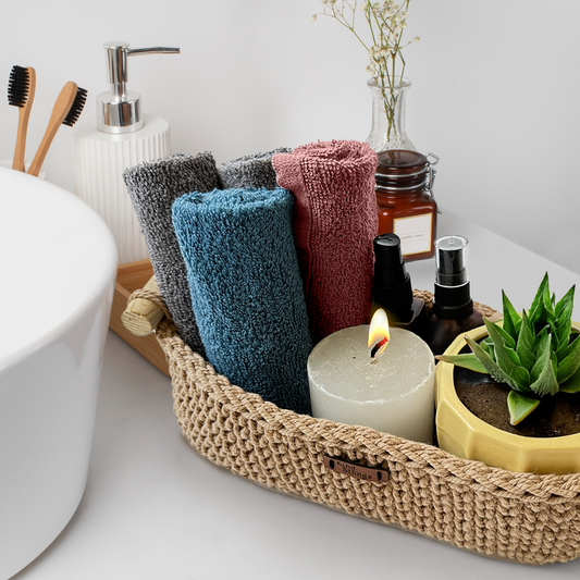 Bathroom counter with towels, candles, and a plant in a woven basket.