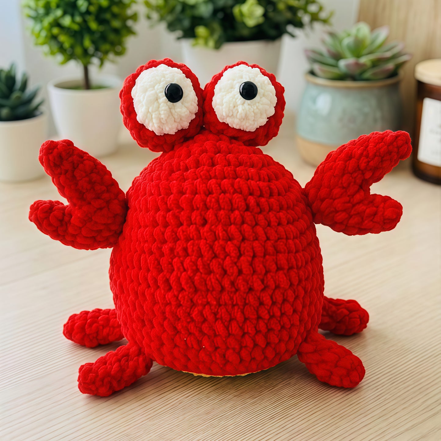 Red crochet crab toy on a wooden surface with plants in the background
