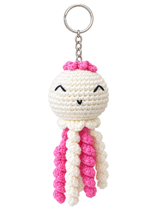 A crochet jellyfish keychain featuring a cream-colored body, bright pink tentacles, and a matching pink bow on its head, attached to a silver metal key ring and chain against a plain white background.
