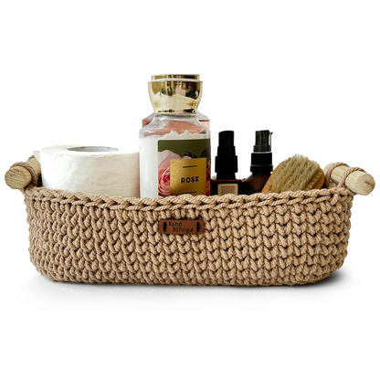 Beige woven basket with various items including a candle and bottles on a white background
