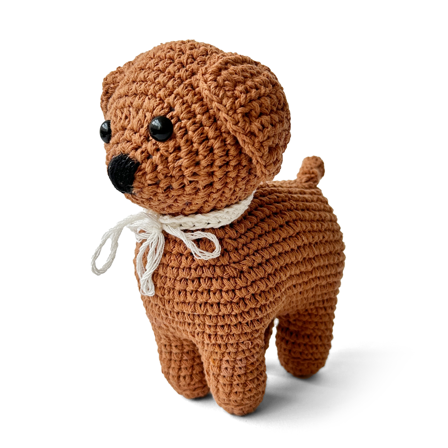 Brown crochet dog toy with a white ribbon on a white background