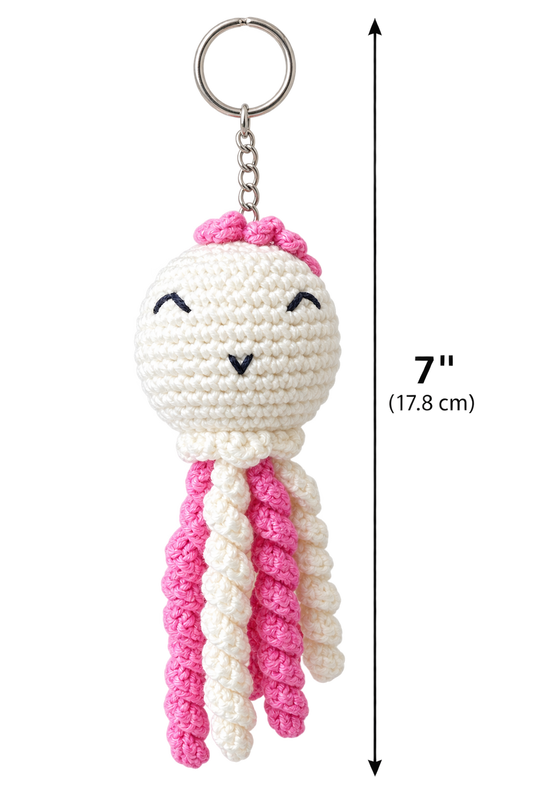 Crochet octopus keychain with a silver metal key ring, featuring a white head with pink hair, embroidered black eyes and mouth, and three long tentacles in white and pink. A vertical measurement graphic on the right indicates a height of 7 inches .