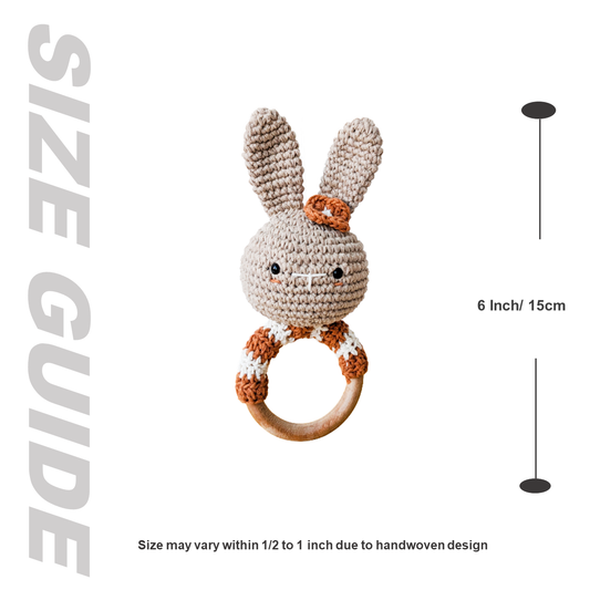 Crocheted bunny rattle with wooden ring and size guide on a white background
