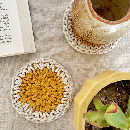 Crocheted coasters with a pot and book on a textured surface
