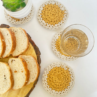 Crocheted coasters with bread and a glass of juice on a white surface