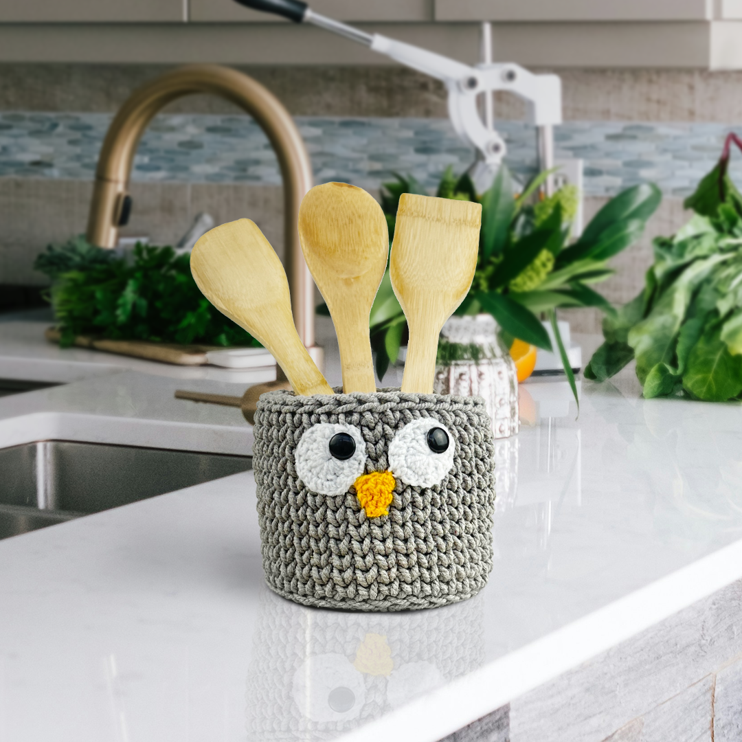 Crocheted owl container with wooden spoons on a kitchen counter