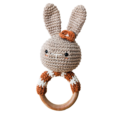Crocheted rabbit rattle with wooden ring on a white background