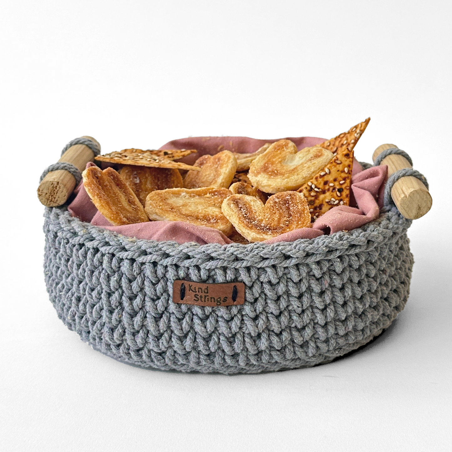 Gray knitted Round Basket with pink Cloth and wooden handles, containing bread slices.