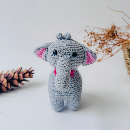 Crocheted elephant toy on a light background with dried plants