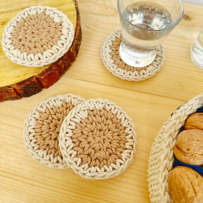 Set of crocheted coasters on a wooden surface with a glass of water and a basket of bread.