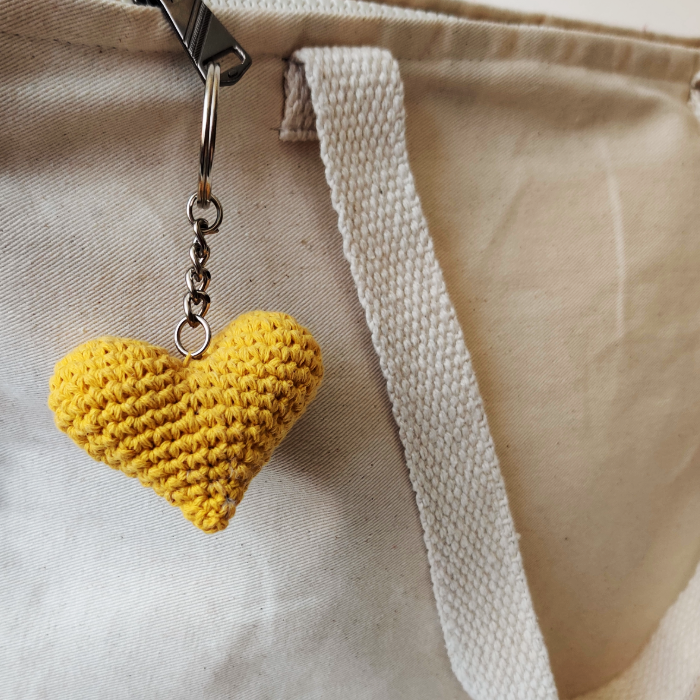 Yellow heart-shaped keychain attached to a white bag.