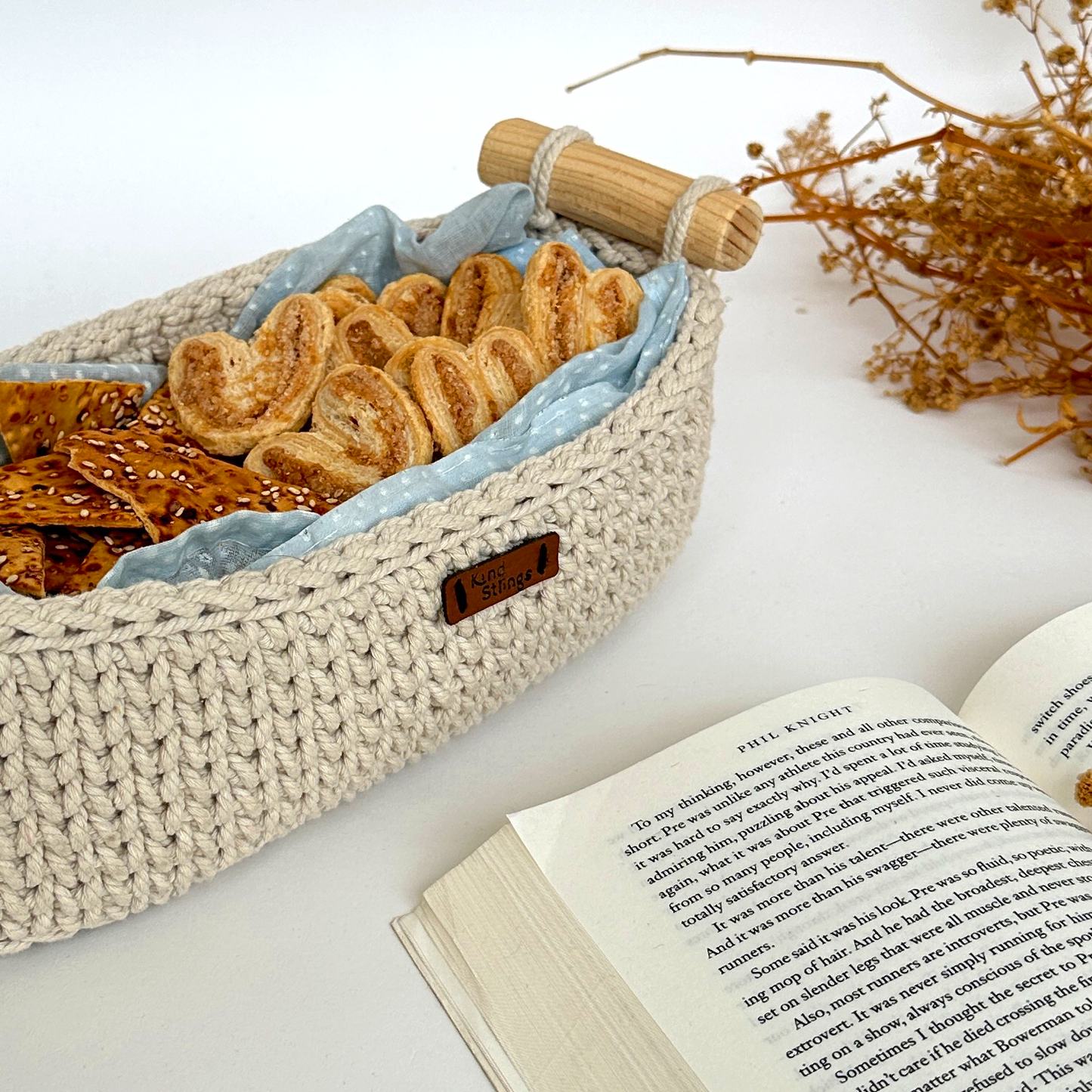 Woven basket with crackers on a surface next to an open book